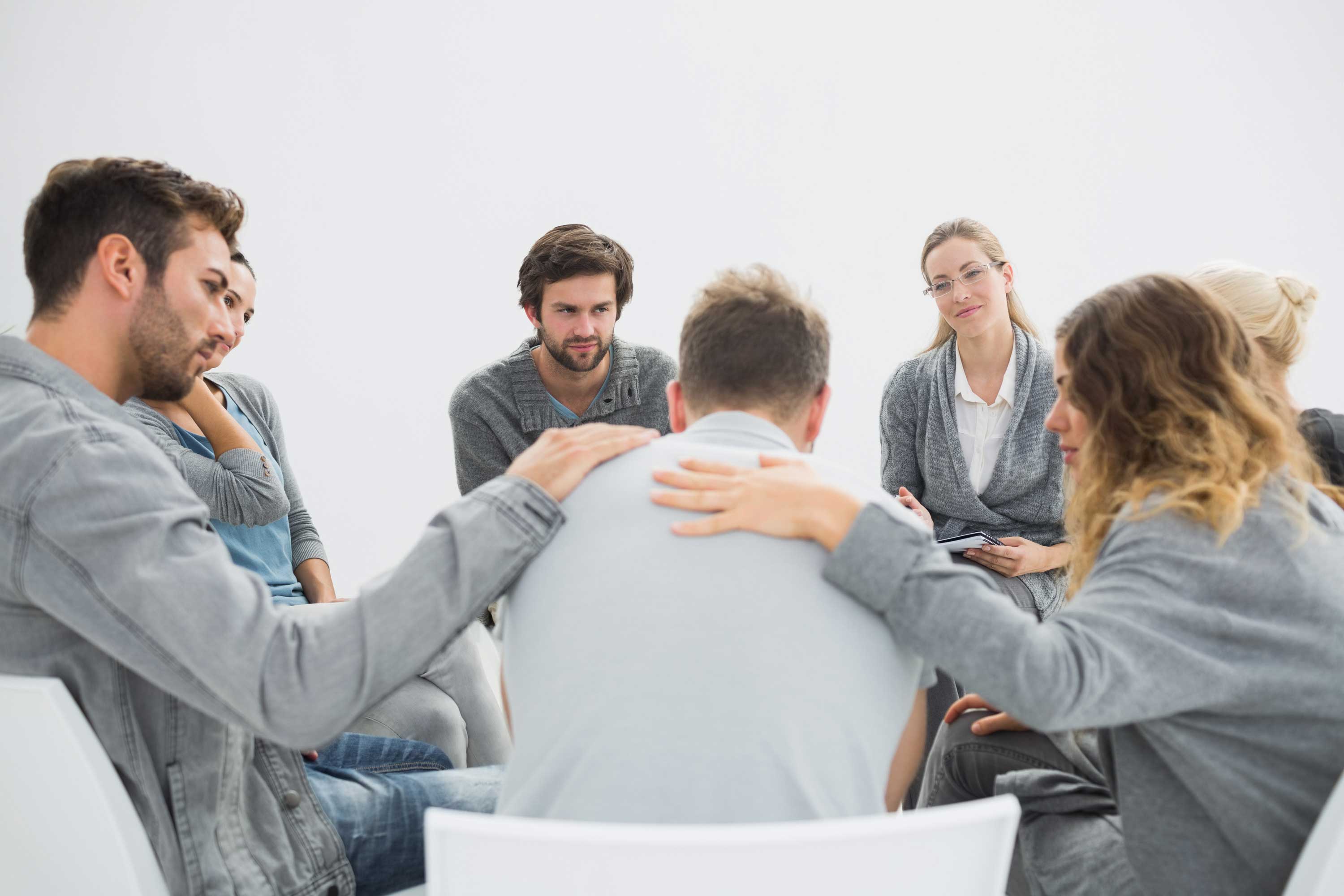 Group therapy in session sitting in a circle with therapist