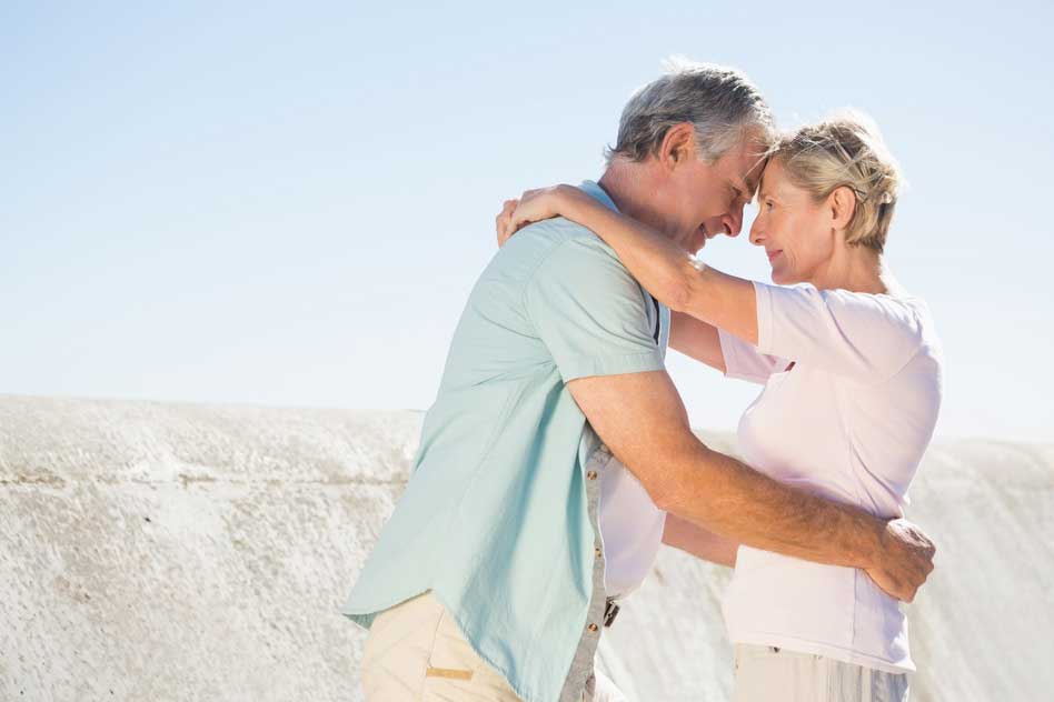 Happy senior couple embracing on the pier on sunny day